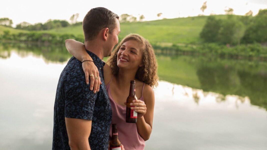woman holding beer bottle while hugging guy